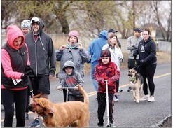 Group of eight adults, two children on scooters, and two dogs on leashes.